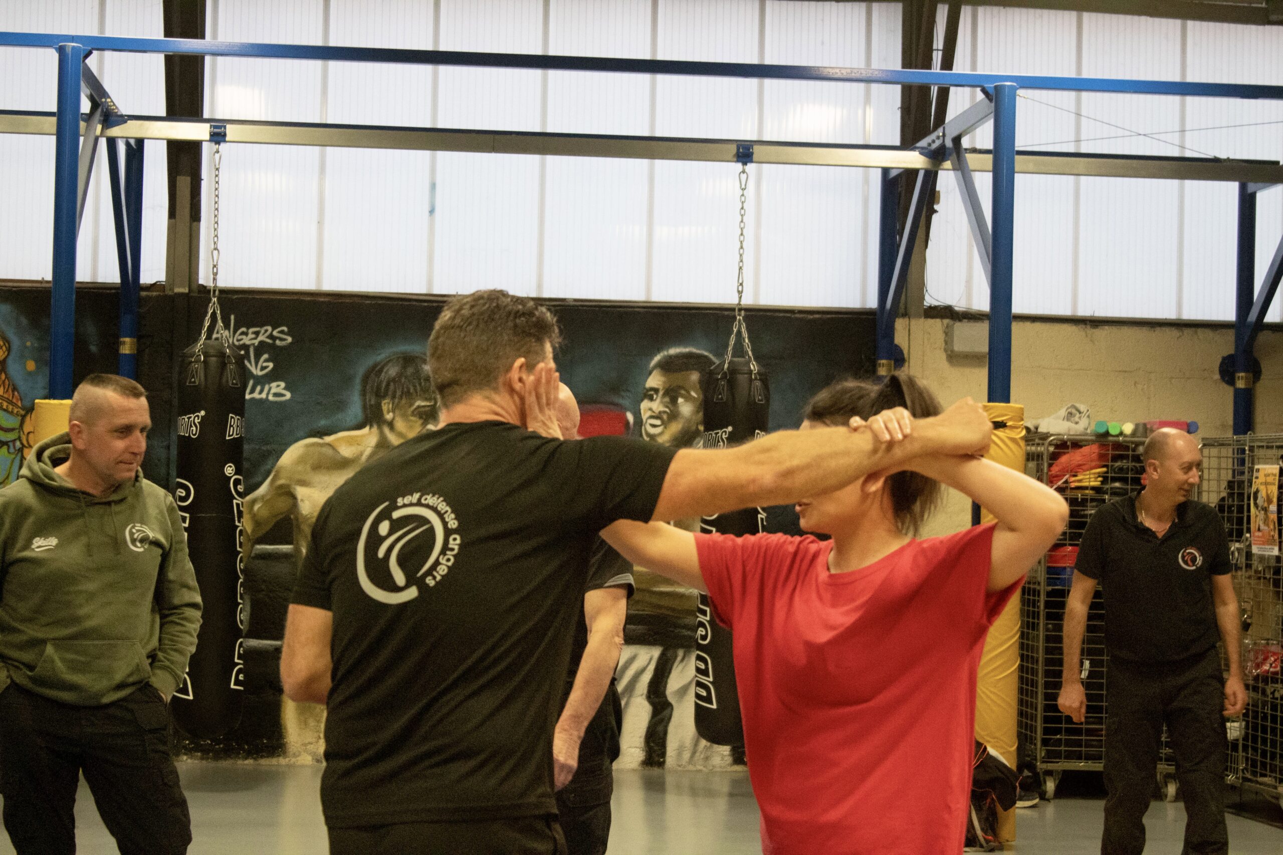 Cours de self-défense en groupe avec un instructeur démontrant une technique de protection.